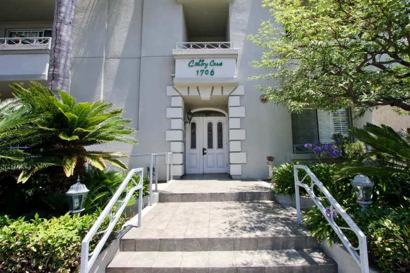 White palm trees and gardens with lamps and flowers in this walk up steps to the entrance