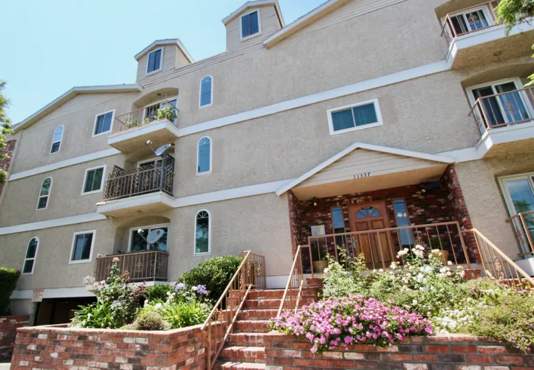large building with small windows with a bricky garden of flowers and shrubbery