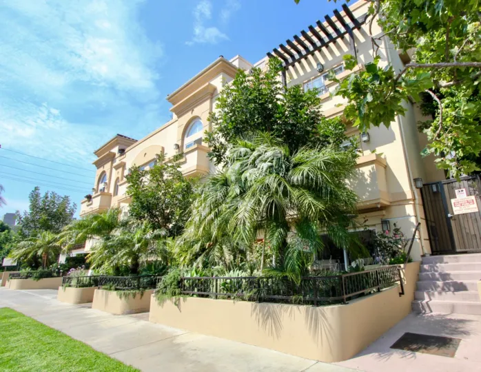 Large palm trees grow outside the windows to provide shade and privacy along the sidewalk