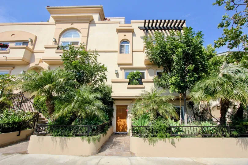 Large condos with big windows and palm trees with garden fences entrances to condows