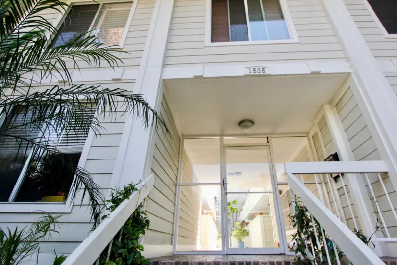 Palm trees planted in front of a Cream colored building at Granville Villas in West LA California with house number1838