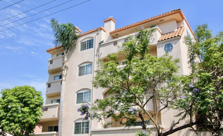 post wire is infront of house and house contains many windows and trees contains flowers and house constructed with shell and balcony contains window