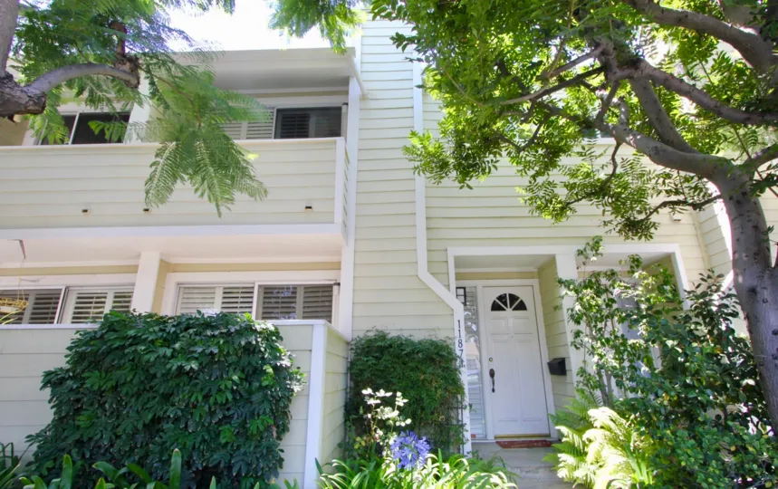 Entrance to Nebraska Manor Townhomes with white door, trees and bushes