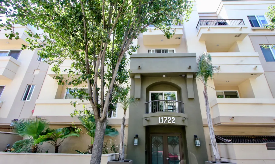 Apartment building with several balconies and trees and front entrance