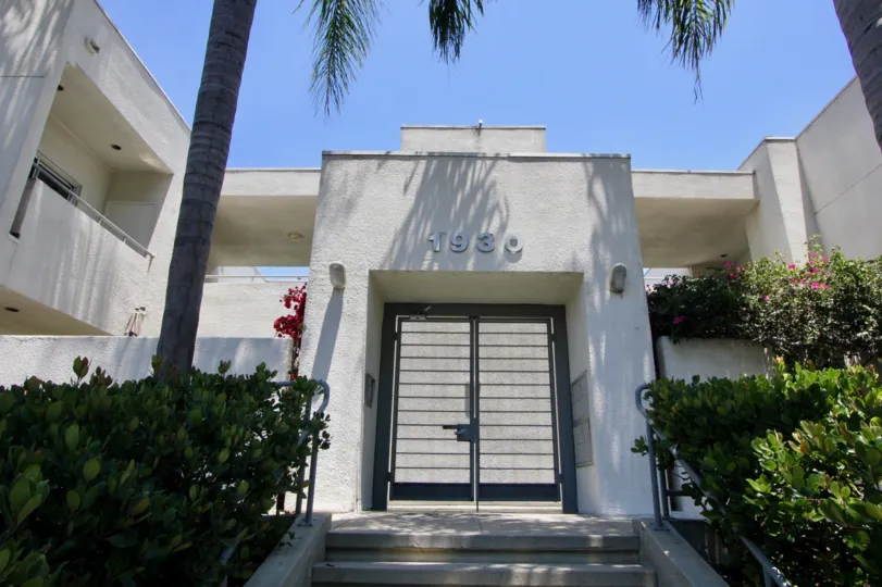 Front walk up entrance almong shrubbery flowering vines and palm trees
