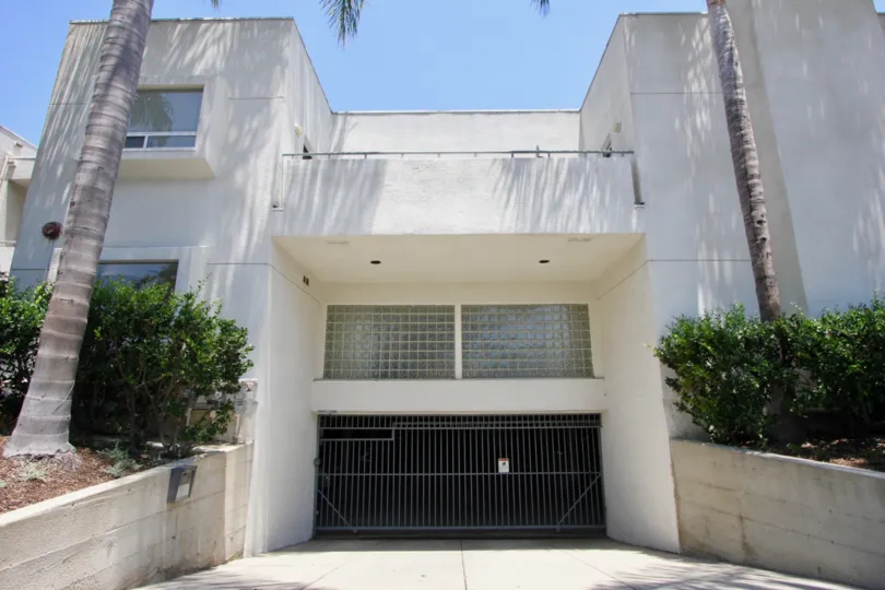 Two palm trees planted at the left and right in front of a Cream colored Building at Purdue Pacific in West LA California