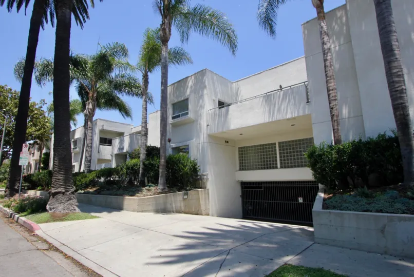 Palm trees taller than the Cream colored apartment houses at Purdue Pacific in West LA California are planted in front of the houses.