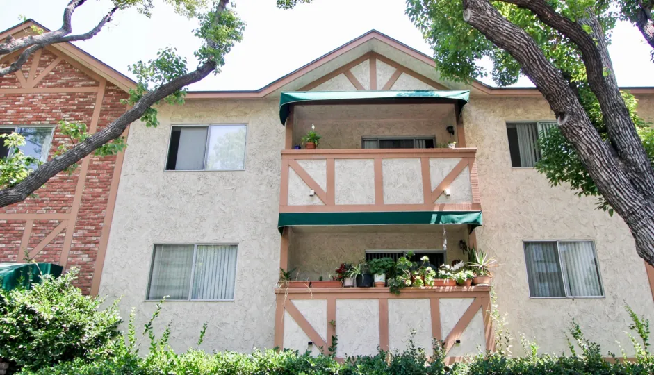 Criss Cross Applesauce house with brick and tree lined shrubbery with balconies and potted plants