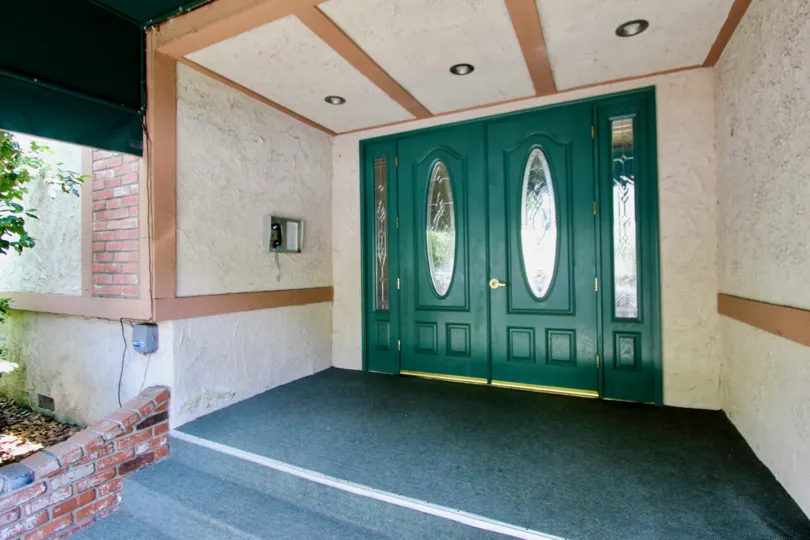 brick is broken in front of side of house near steps and door contains glass mirror door