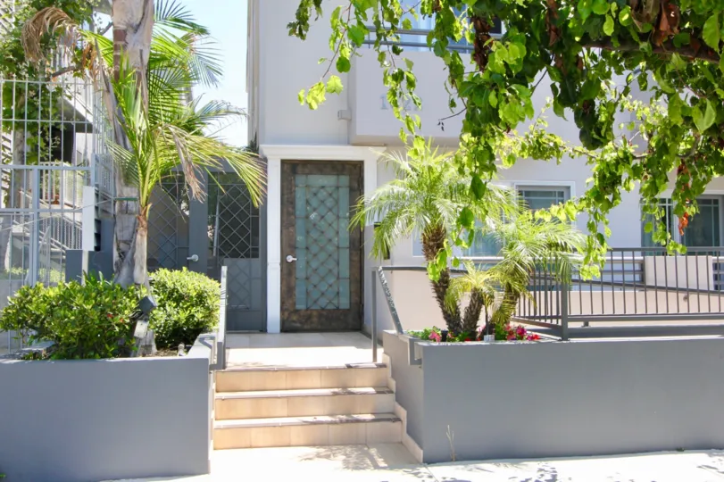 door is cloesd and door contains gate and glasses and trees are in front of house with flowers arranged