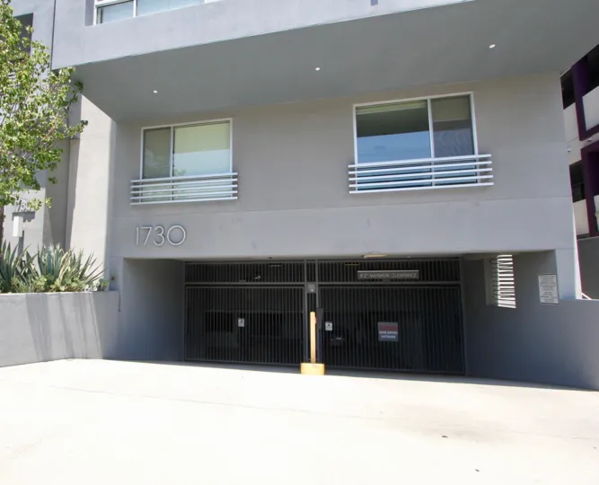ceiling lights are in the house and it is on and house gate is closed and tree are side on house and windows are opened in balcony