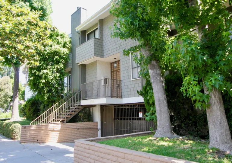 a sunny day and there is a wooden stair case in house and gate is closed in house