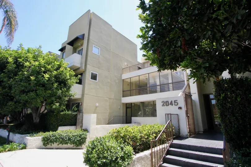 Shade and palm trees planted at the Cream colored apartment building at the Pines in West LA California