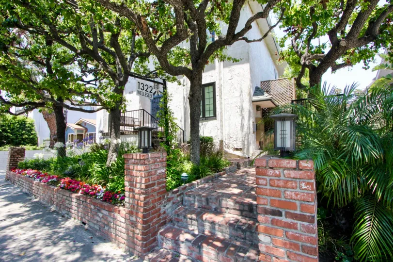 Older white brick and fancy trees create a unique look of curb appeal at this condo
