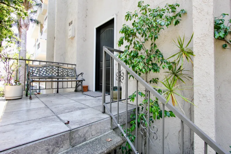 Upper balcony with trees growing up the side and a park bench where you can sit and put your shoes on