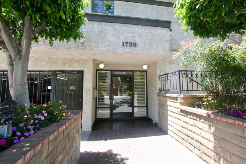 A sunny day in the Westbury Condos Townhomes a beautiful house and trees.