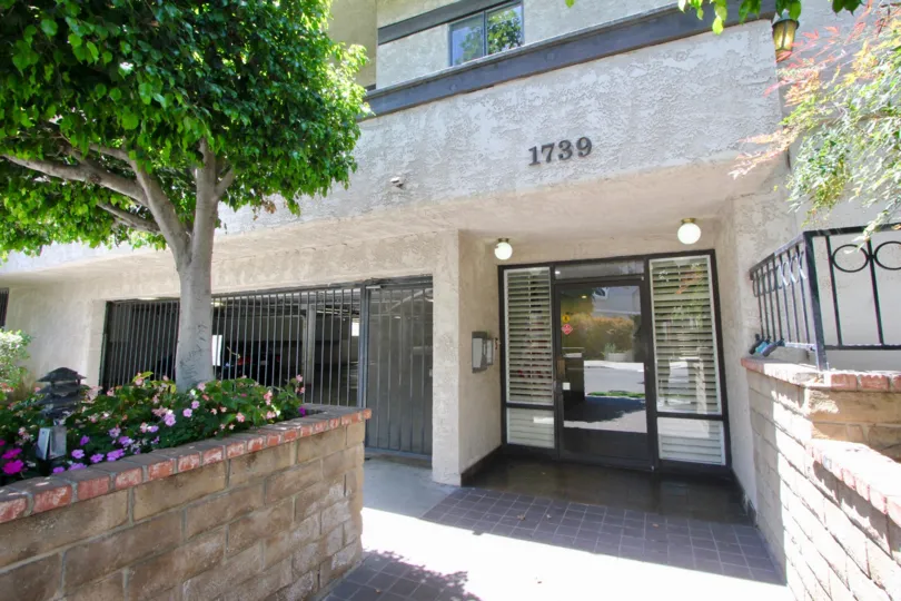 cement gray condo with black window door, white blinds. really nice sunny day with a garden view