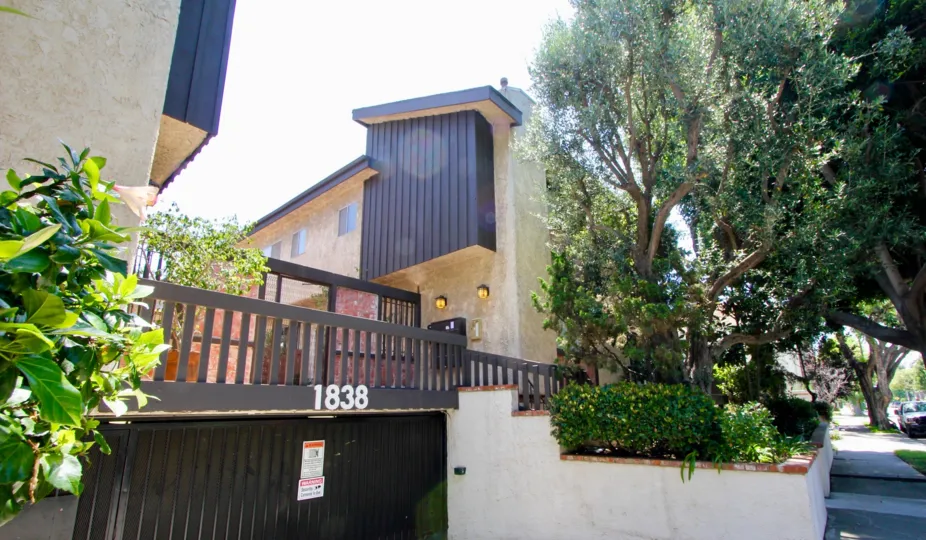 Green flowers and plants planted at both sides of the Underground parking entrance of A brown colored house with black roof at Westside Townhouse in West LA California