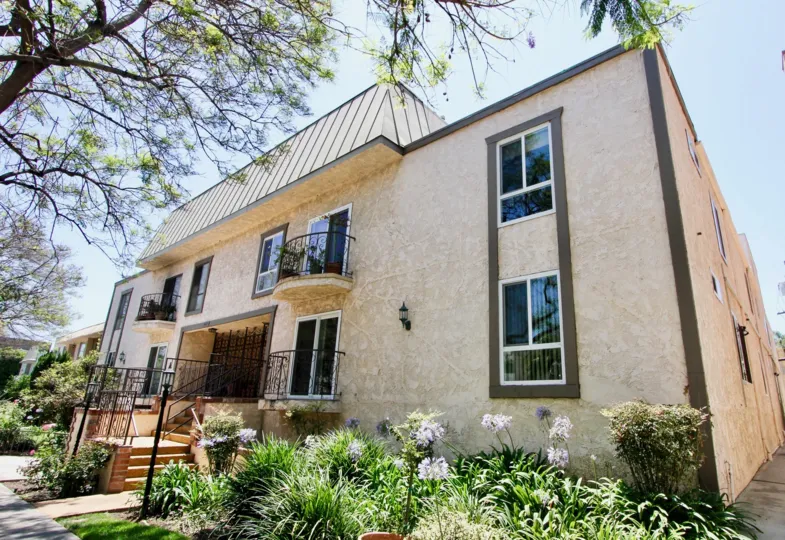 A tan house at 1827 Greenfield with black railings and green plants in front of it
