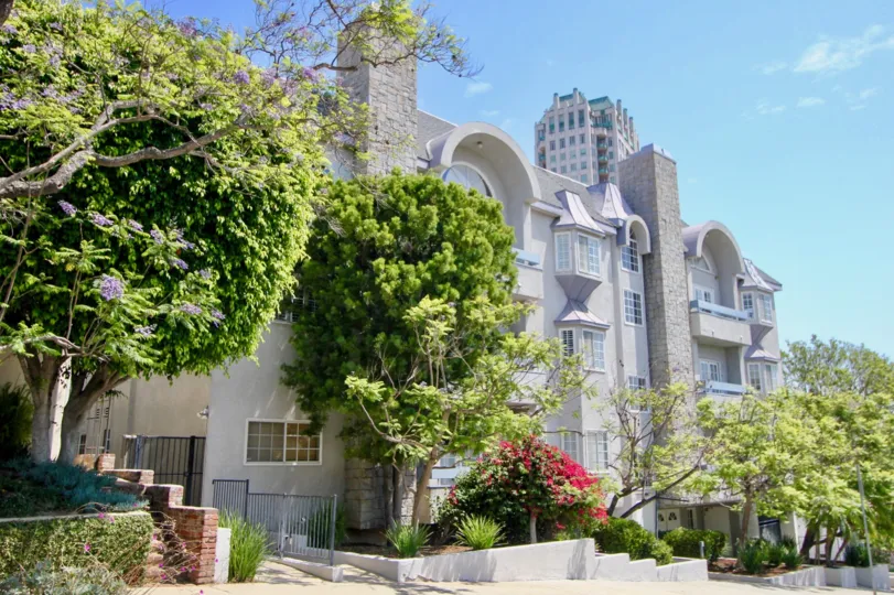 The regal Ashton Place on a sunny day. Trees and greenery line the sidewalk.