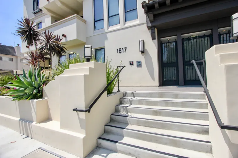 Front exterior view of front door, steps, balcony, and plants at Avenida Prosser in sunny Westwood, California.