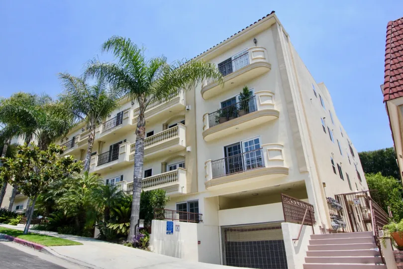 A street view of Century Fox Hills, and cream residential building on a slanted street with indoor parking.