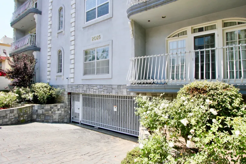 Exterior view of balcony, garage gate, and bushes at Chateau Glen in Westwood, California on a sunny day