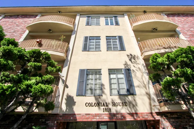 Colonial house building have three floor with balcony and flower pots, tree.