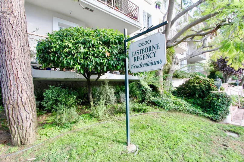 In the Outside of Eastborne Regency condominiums was decorated with plants and having name board post.