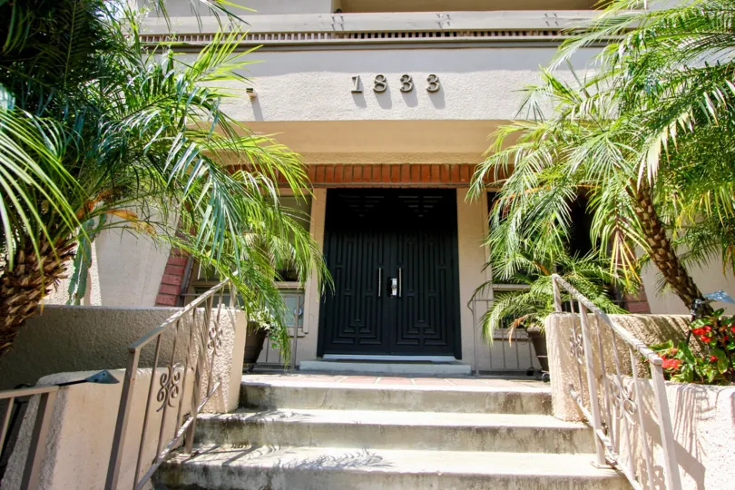 A sunny afternoon at an entrance at Fairburn Lencrest with palm trees and flowers.
