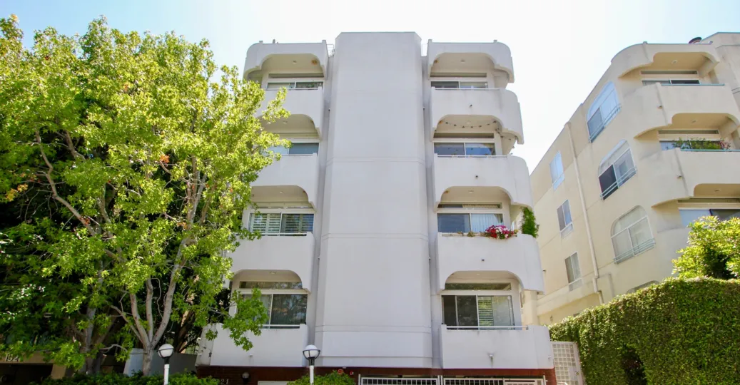 A lovely day at The Glendon House Westwood, a residential building with multi stories, and a well lit walkway.