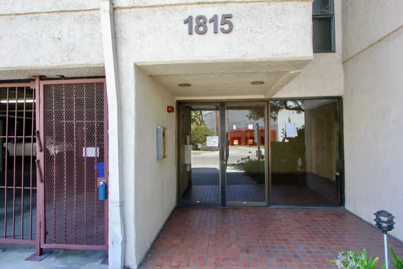 A white building in the Glendon Villas community with a glass front door and red gate