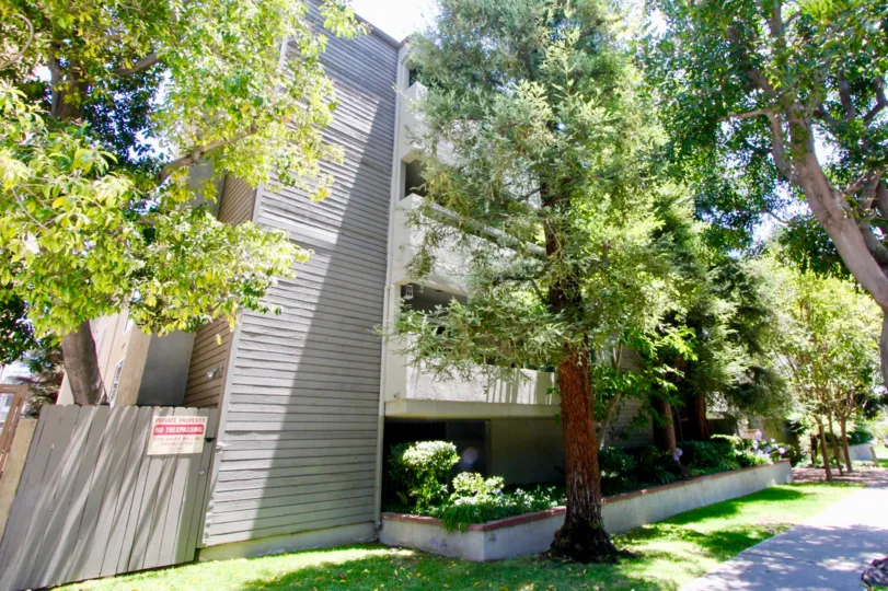 A bright day in the Greenfield East with an ash color apartment and trees.