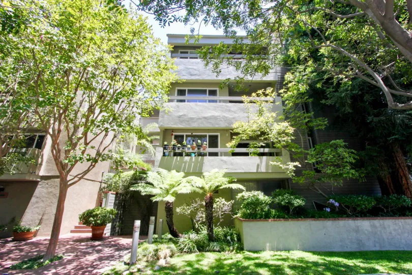 A building with lanscaping filled with several types of trees and plants in Greenfield East