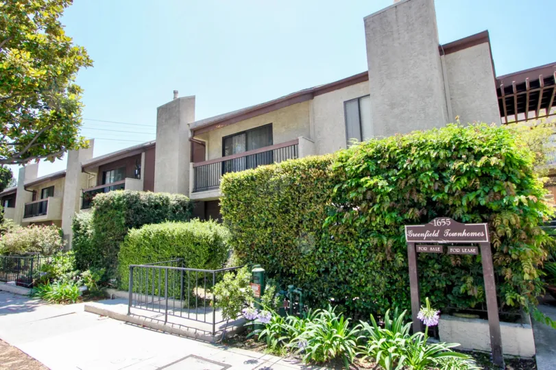 A sunny day in the Greenfield Townhomes with beautiful apartment and a big tree infrond of the apartment.