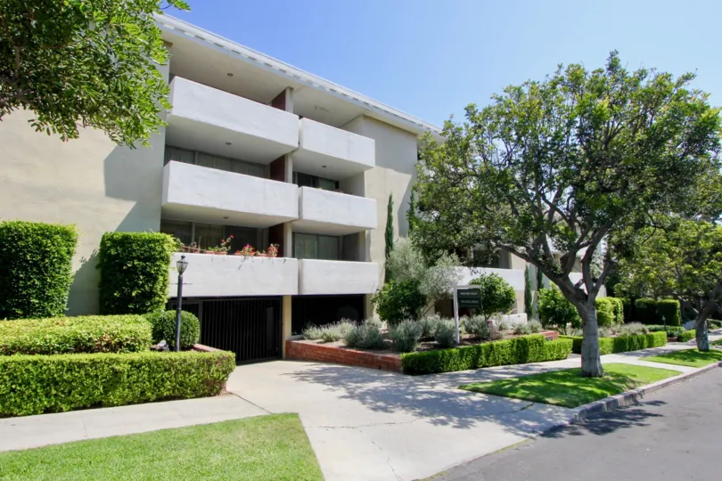 Balconies on a sunny day, with mature trees and well-trimmed hedges in Kinnard Westwood, California