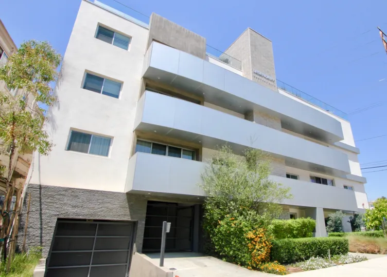 Front of Legendary Century City community on a sunny day with trees and bushes.