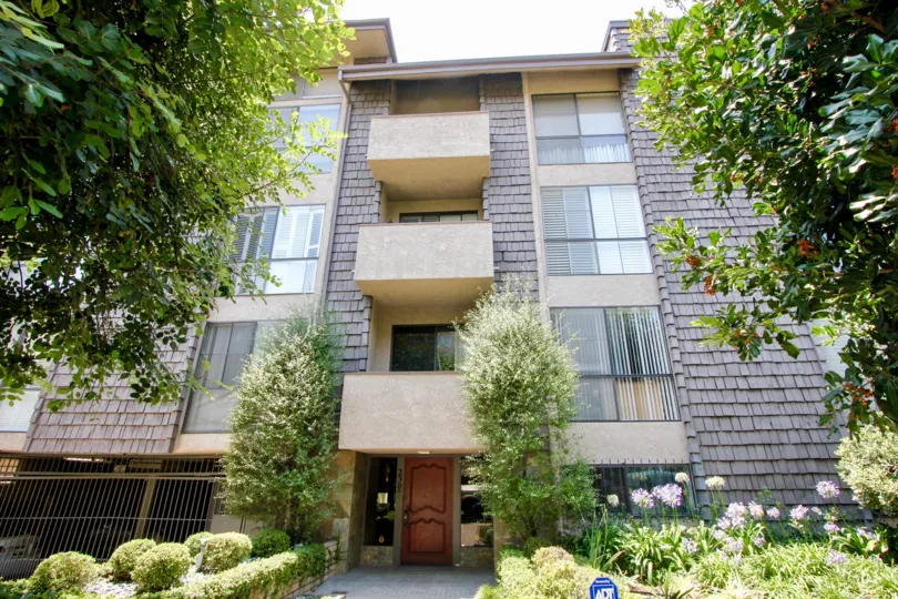 A brown house in the Park Century West neighborhood with multiple balconies and green trees