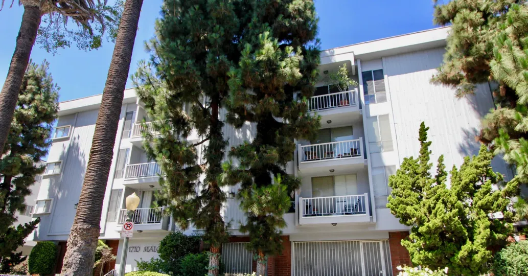 A flat with white balconies and green pine trees in Westwood.