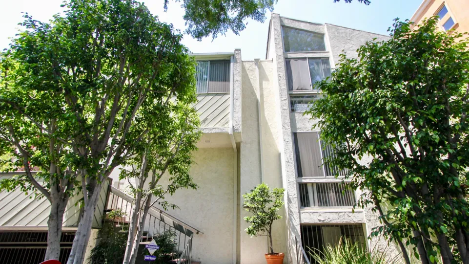 A white building in the Thayer Townhomes neighborhood with tall trees and multiple windows