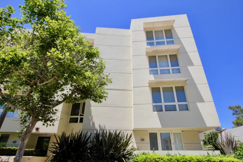 A sun shown facade with tree and shrubbery at The Enterprise Condominium.