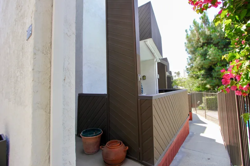 A white building in the Village Townhouses neighborhood with brown fences and pottery