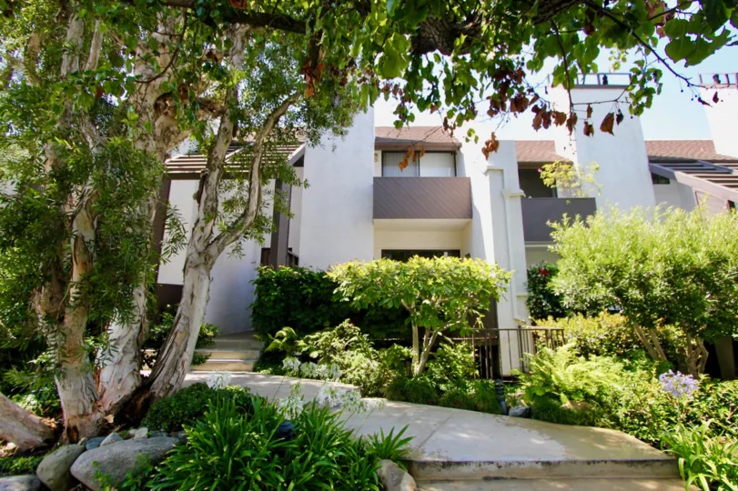 A WHITE COLOUR BUILDING LOOKS LIKE AN APARTMENT AND SOME TREES ALSO NEAR TO THE BUILDING