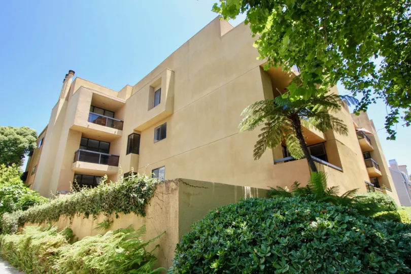 A sunny day over the bush filled facade at Walden Condos in Westwood.