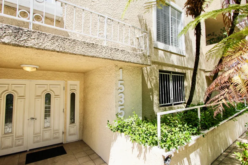 A white house in the Westwood Bentley neighborhood with a white front door and white railing