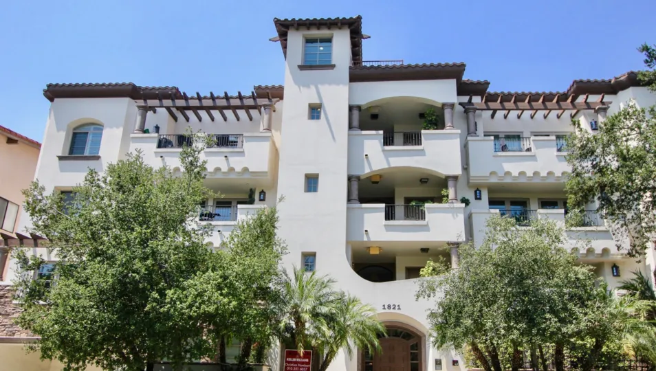 Views of the front of the Westwood Fairburn with plush trees and intricate balconies