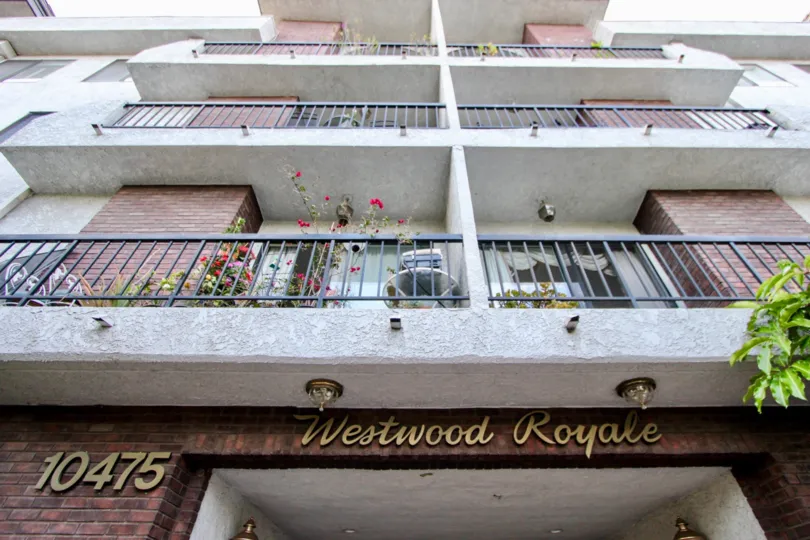 Image of front of apartment building with three floors displaying balconies.