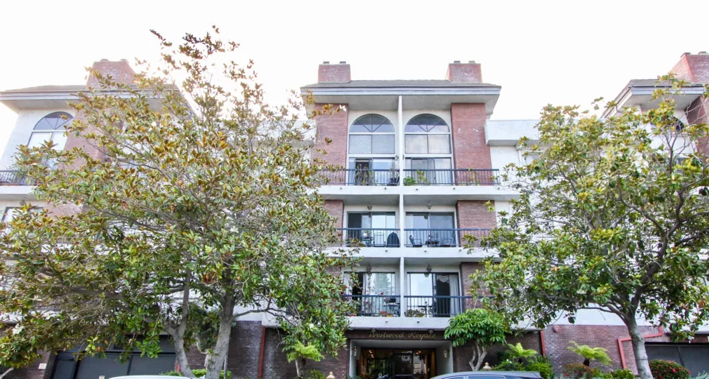 A lovely day at The Westwood Royale, a red bricked residential building with large windows.