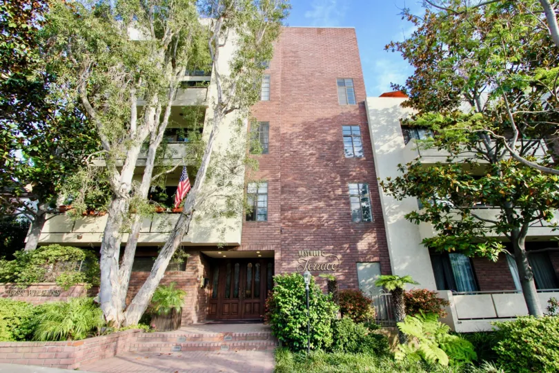 Westwood Terrace surrounded by trees and shrubs with brown wall.