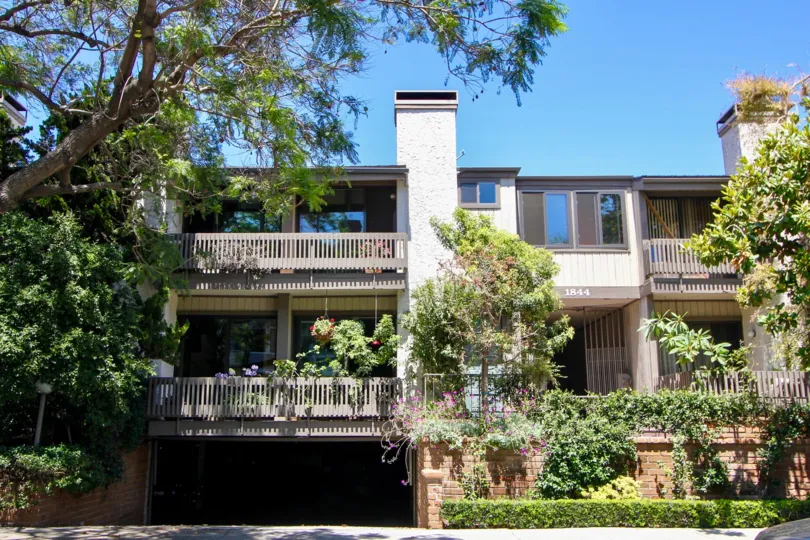 A sunny day in Woodvale Village with an attached house with an undergound garage surrounded by trees